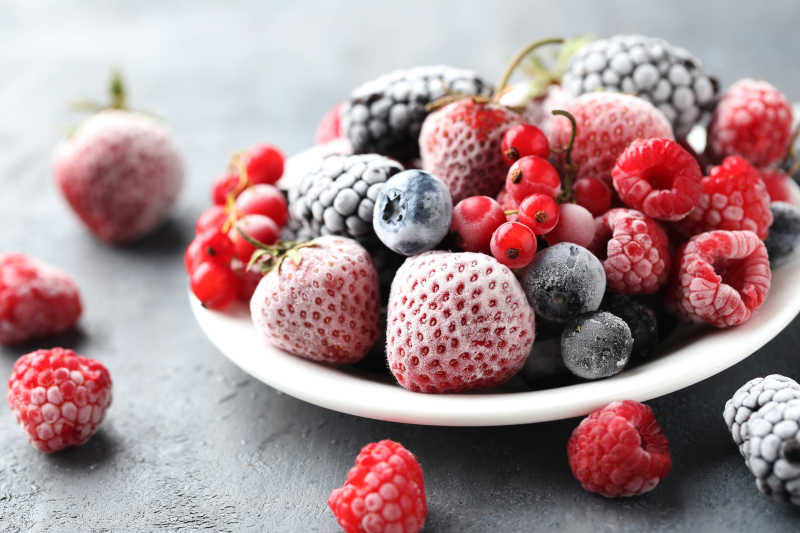 黑木桌上美味新鲜的冰冻草莓蓝莓等浆果