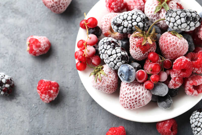 白色磁盘中美味的冰冻蓝莓草莓覆盆子越桔等水果