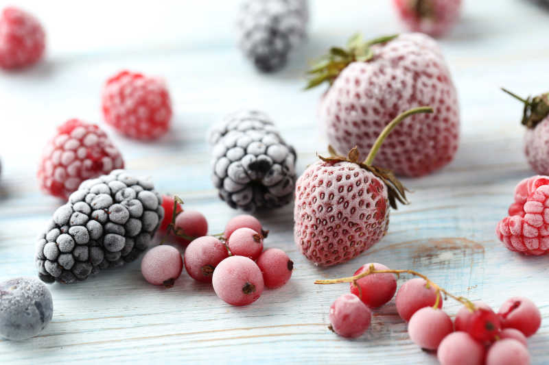 木桌上的冰冻的草莓覆盆子等水果
