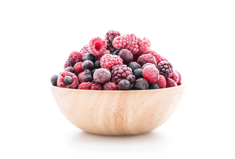 白色背景下木碗里的蓝莓草莓等冰冻浆果