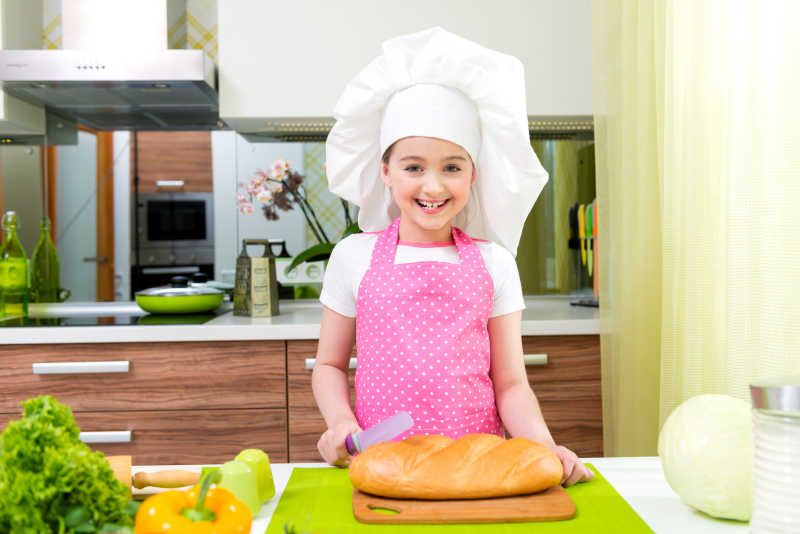 小女孩在厨房切法式面包