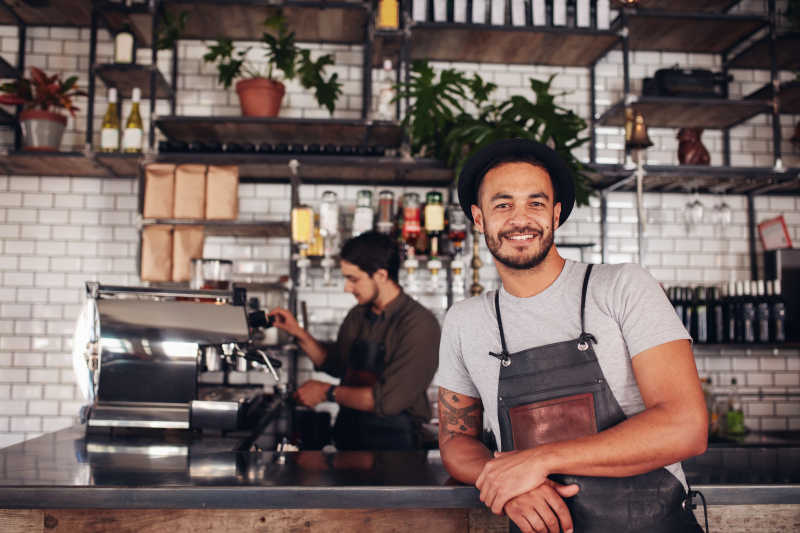 咖啡店背景前微笑的男服务员