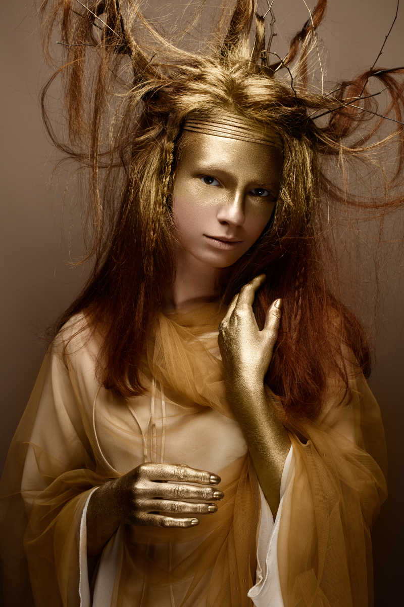 棕色背景前画着金色艺术妆容的美女