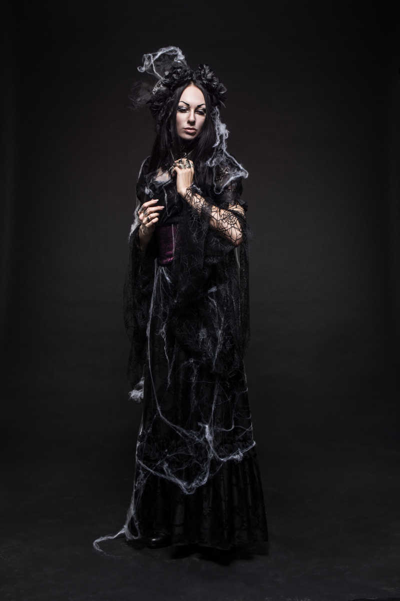 黑色背景下美丽的哥特式女人穿着黑色连衣裙