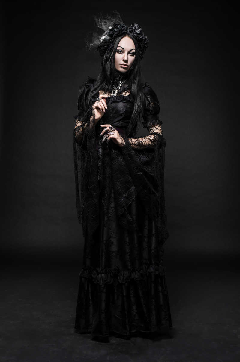 美丽的哥特式女人在暗黑的画室中穿着黑色连衣裙