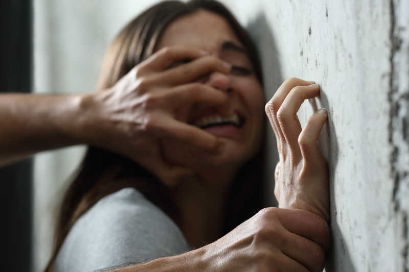 男人用手将女人的头和手按在墙上