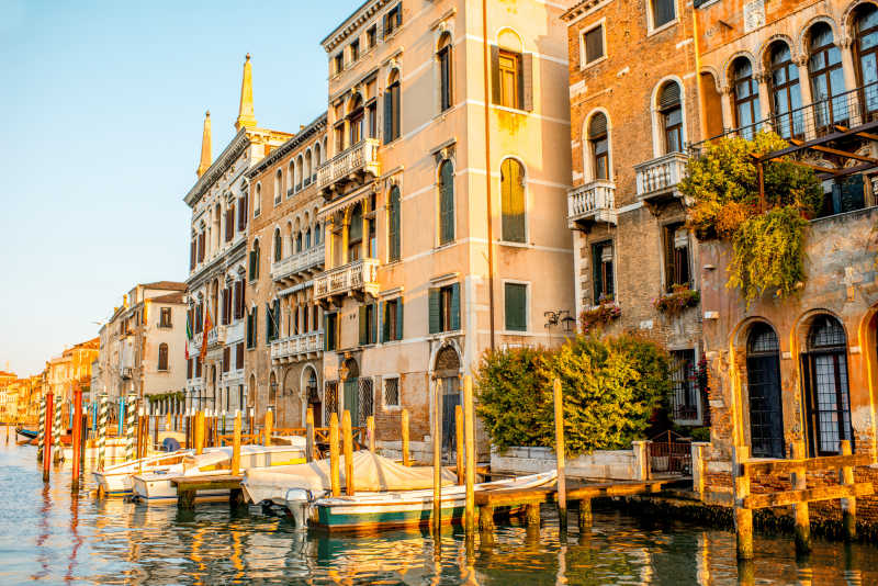 日出-日落下威尼斯运河边上的哥特式建筑和小船