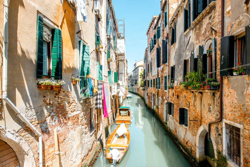 晴天背景下的威尼斯建筑之间的运河和小船