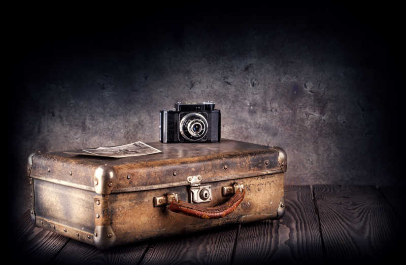 旧木板上的老式手提箱和复古相机