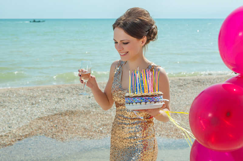 沙滩上拿着酒杯和蛋糕穿着礼服的美女