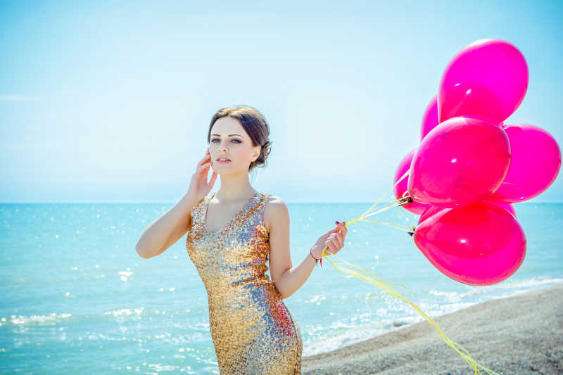 海边沙滩上拿着气球的美丽女人