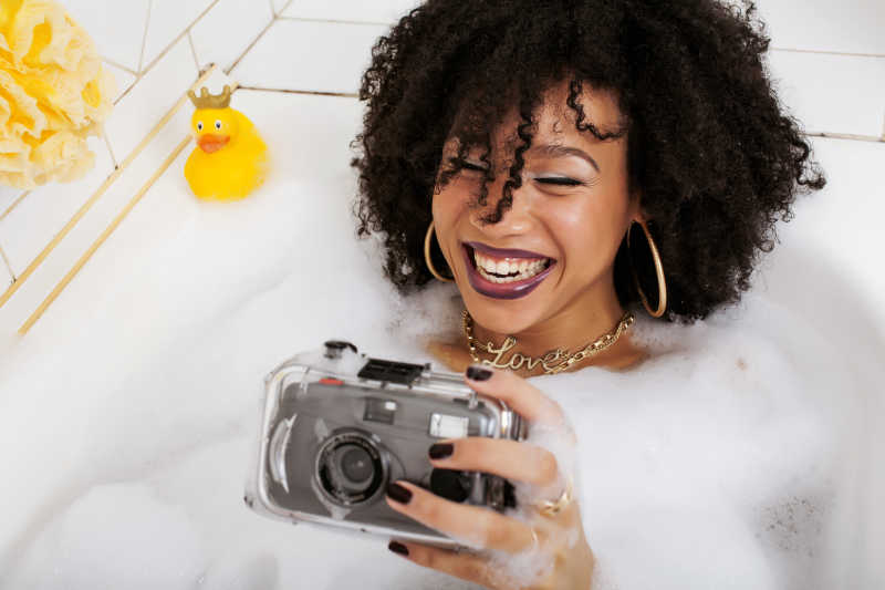 黑人少女泡在浴缸里拿着相机在自拍