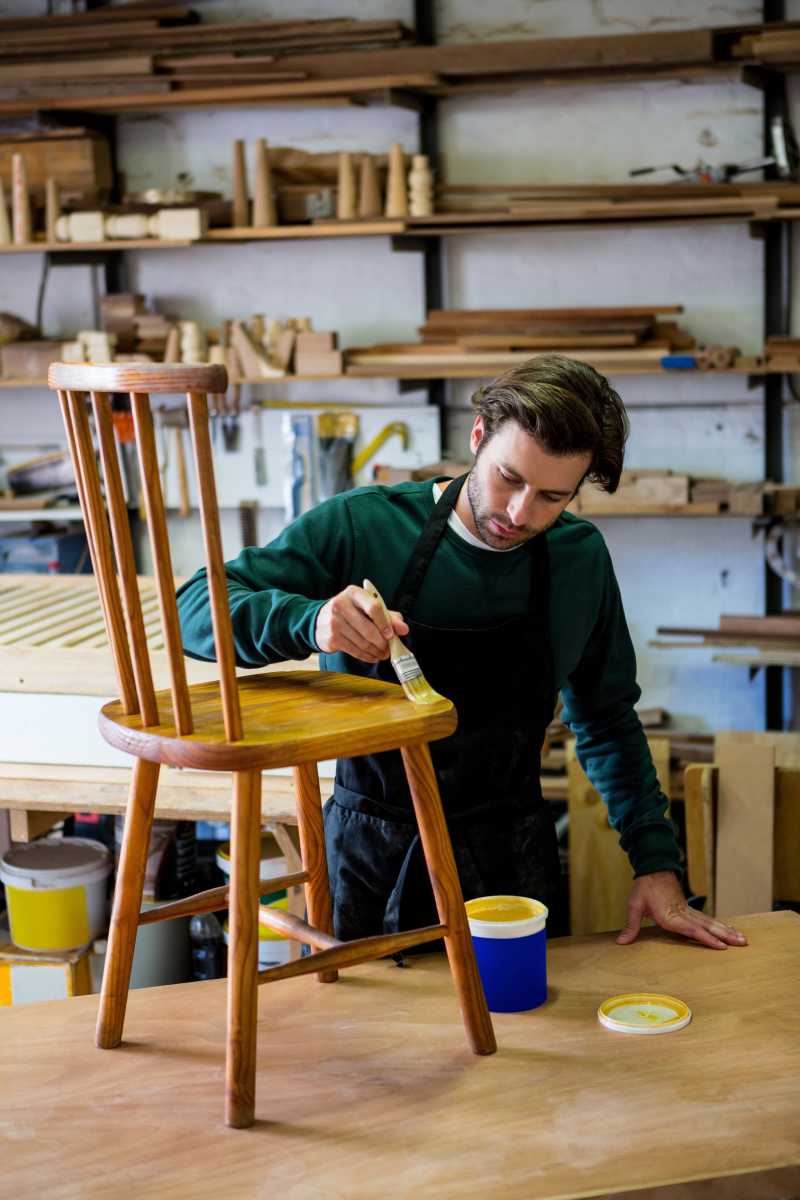 在为椅子上油漆的木匠