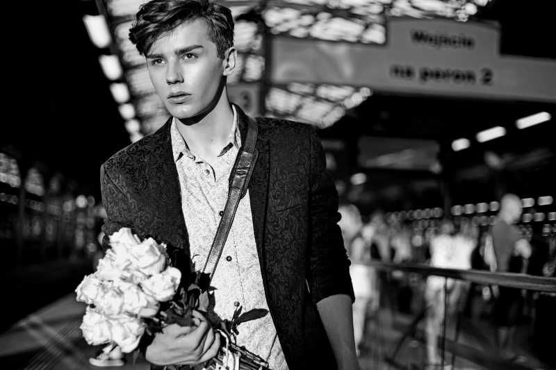 站在火车站的迷人男人手拿玫瑰花黑白照片