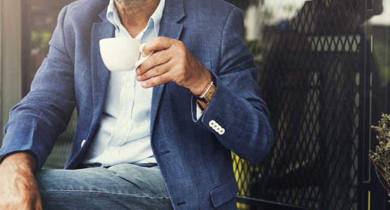 坐在室外喝着咖啡的男性商人
