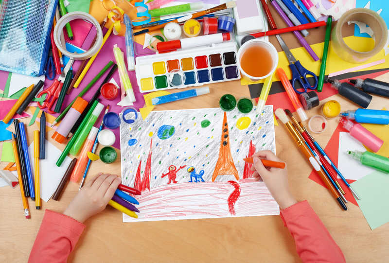 书桌上杂乱的绘画工具和正在画画的儿童