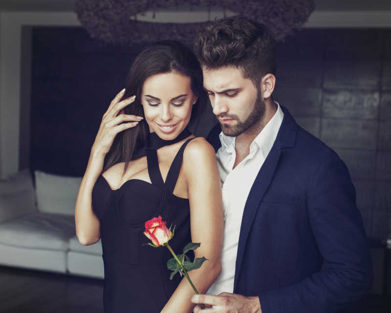性感年轻浪漫男人把玫瑰献给时尚女人