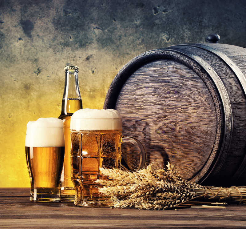 木桌上的木桶和成熟的小麦以及倒满的啤酒