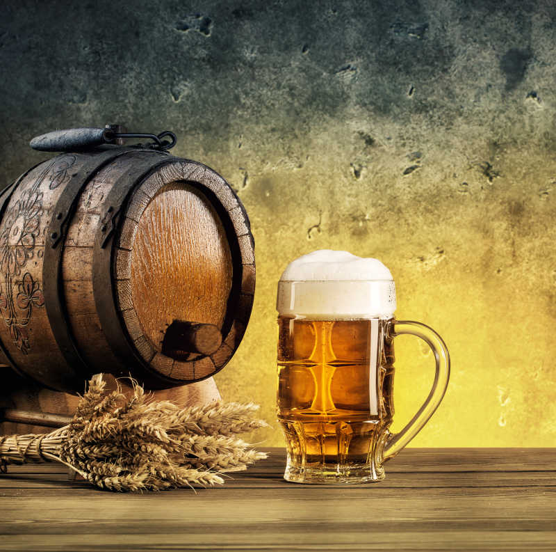木桌上的木桶金黄色的小麦以及一满杯啤酒