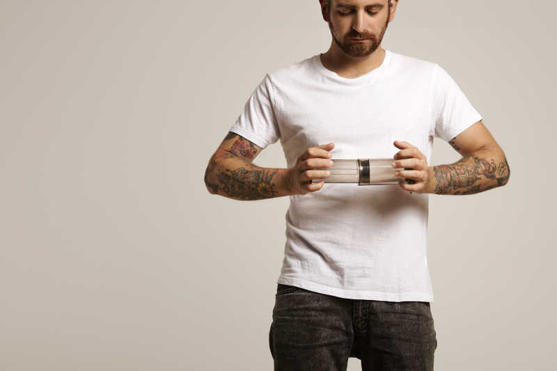 手臂有纹身的帅哥拿着小型咖啡机