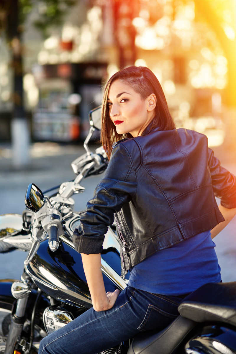 阳光下街道边坐在摩托车上回头的性感女孩
