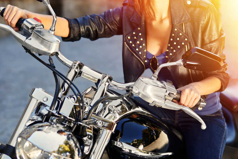 阳光下灰色路面上坐在摩托车上的性感女孩