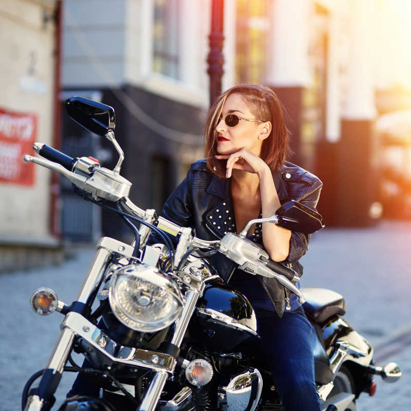 有阳光的马路边上坐在摩托车上的性感女孩
