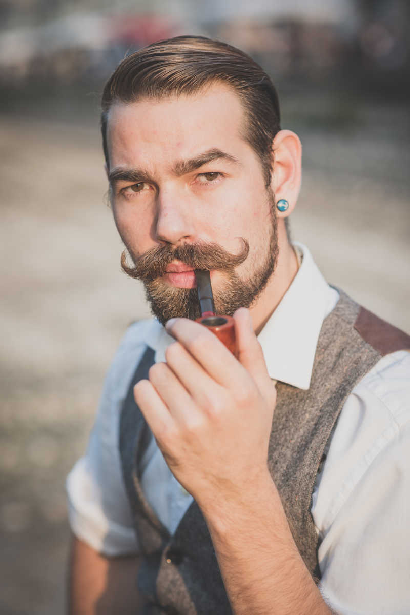 留着漂亮大胡子的男人在抽着烟斗