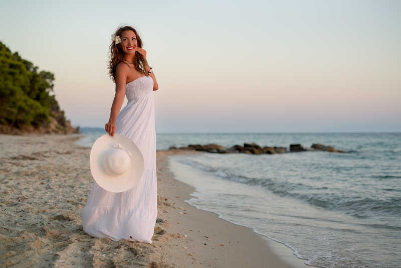 海滩边穿白裙的年轻漂亮的女人