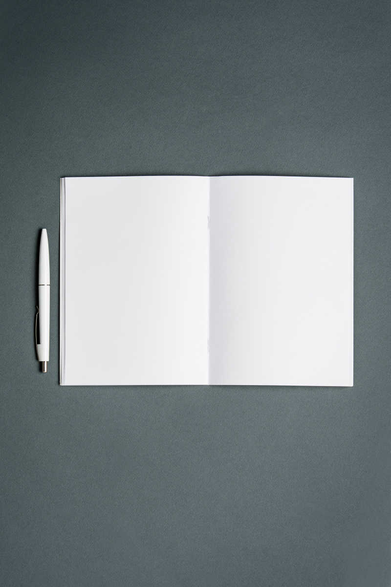 灰色背景上空白的笔记本的笔