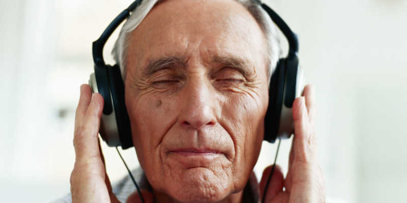 闭着眼睛享受耳机里的音乐的老人