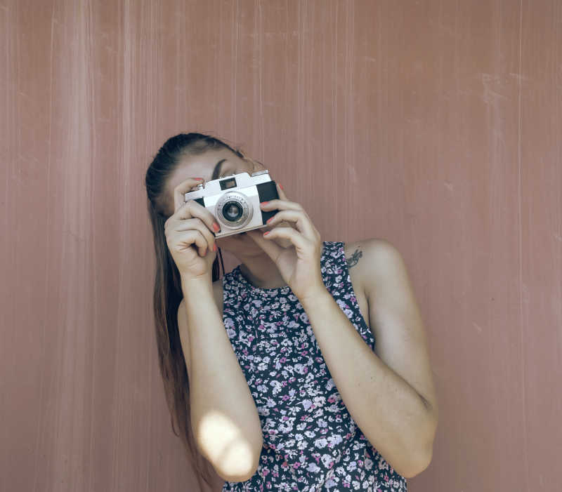 木制背景前女孩拿着老式相机拍照