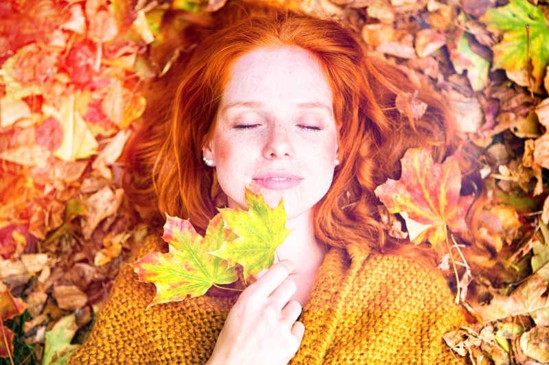 美女躺在秋天的落叶中