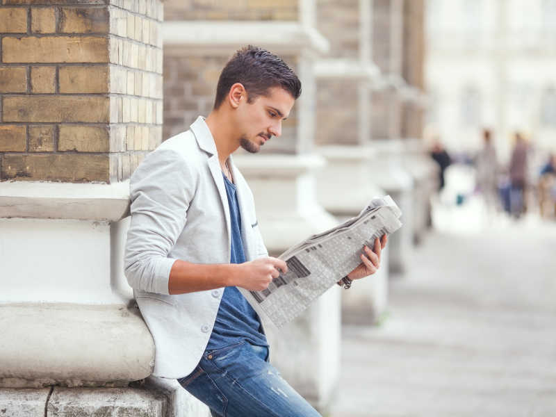 年轻商人在户外阅读报纸