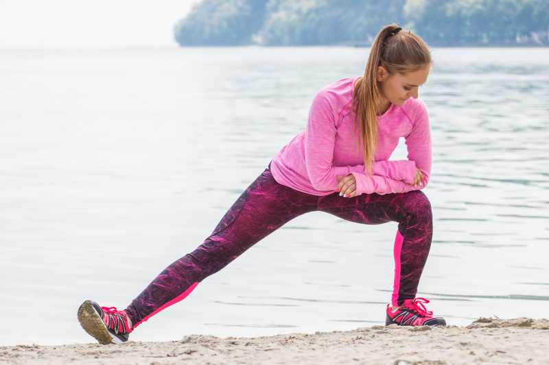 女孩穿着运动服在海滩上锻炼