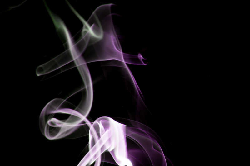 黑色背景上的互相缠绕的紫色白色烟雾
