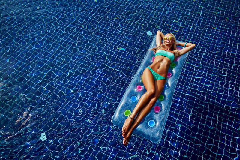 泳池里躺在气垫上的性感身材的年轻女人