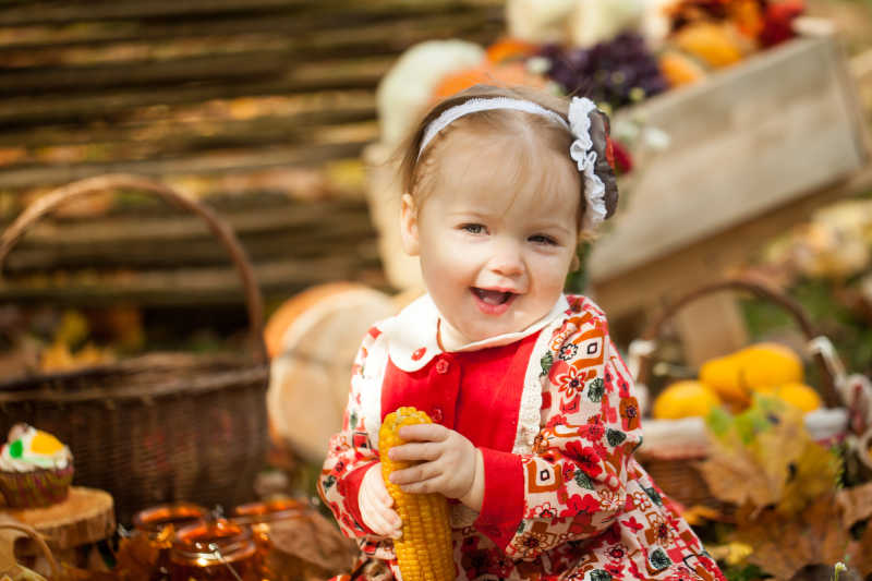 秋天公园里拿着煮玉米的小女孩