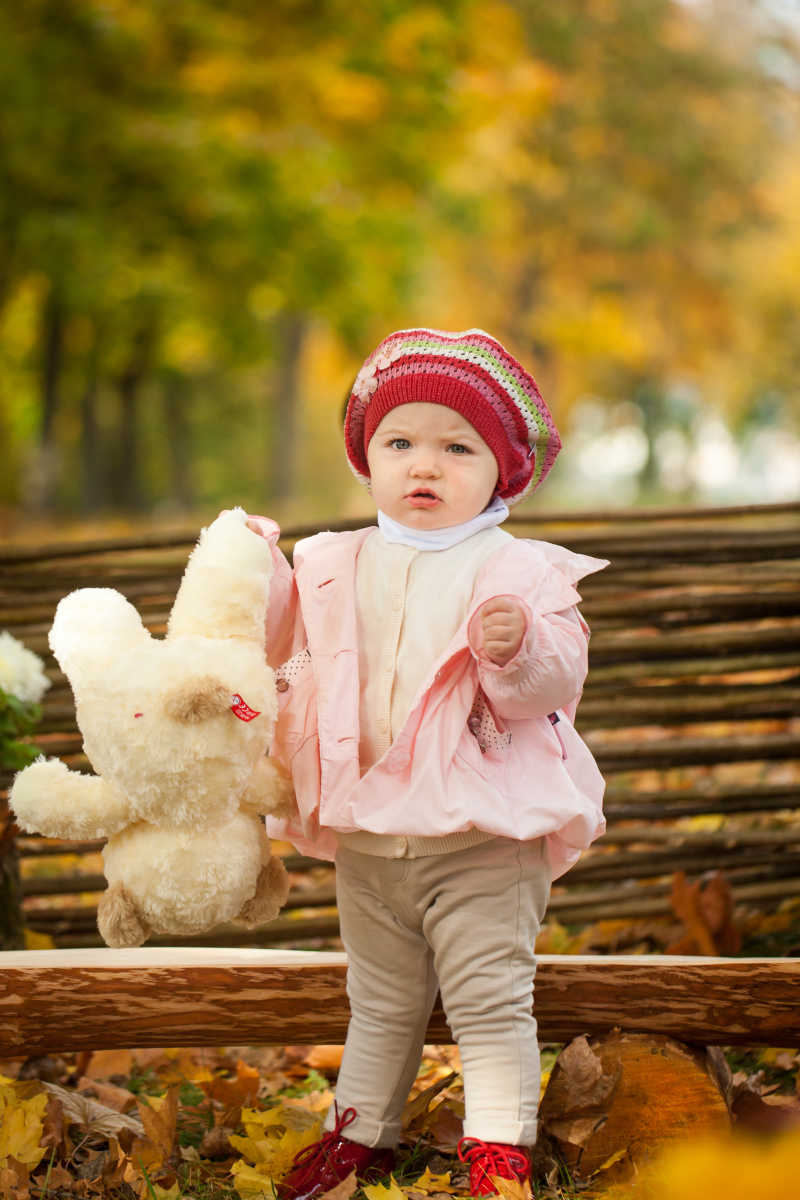 秋冬公园木凳旁的泰迪熊小女孩