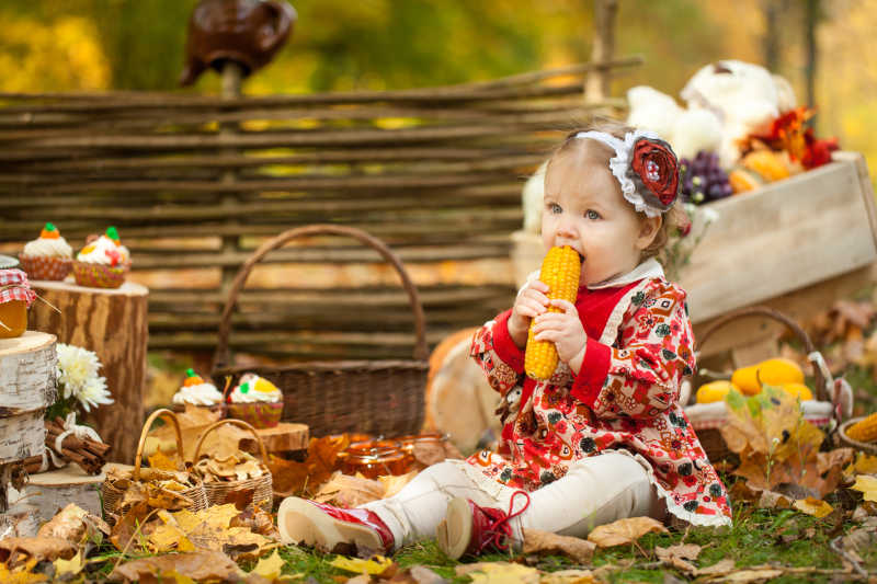 秋天公园里吃煮玉米的小女孩