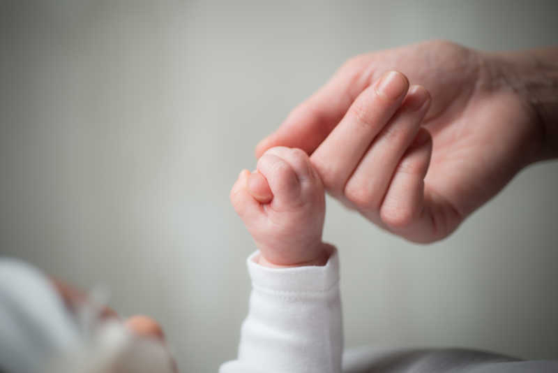 紧握着母亲的手的婴儿的手