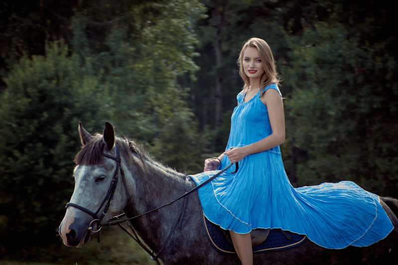 穿着蓝色长裙骑马的女孩