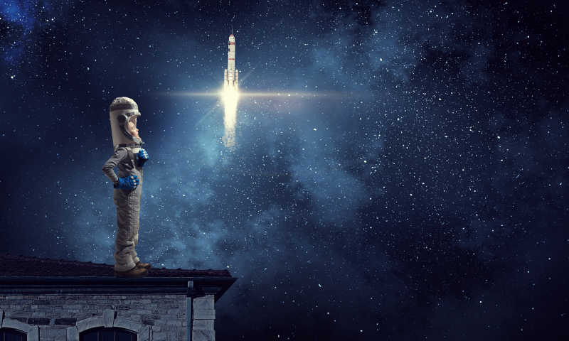 宇航员装扮的小女孩看着升空的火箭