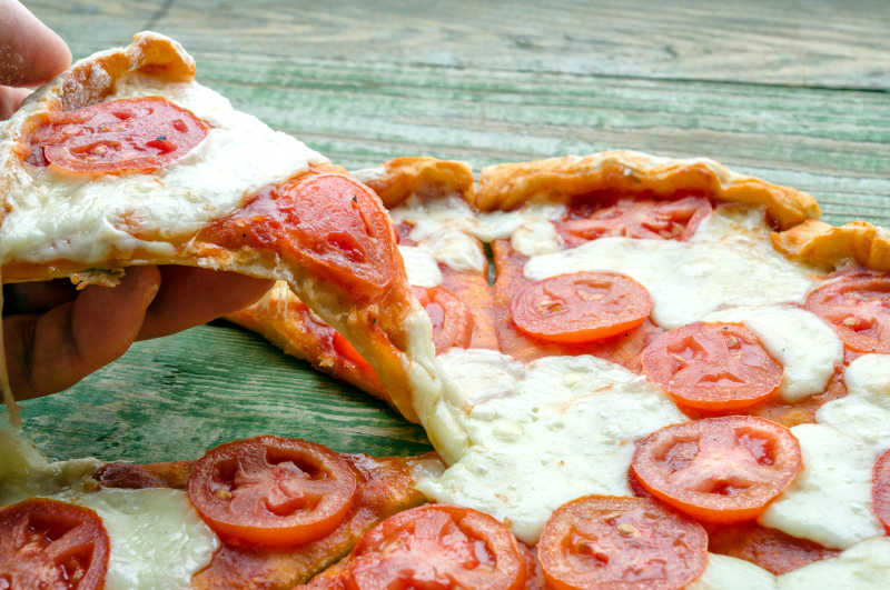 绿色木桌上新鲜美味的西红柿披萨饼