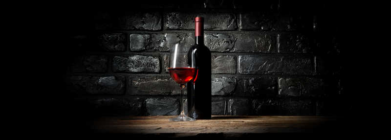 黑砖背景上的红酒和酒杯