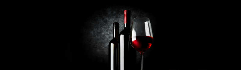 黑色背景上的两瓶葡萄酒和酒杯
