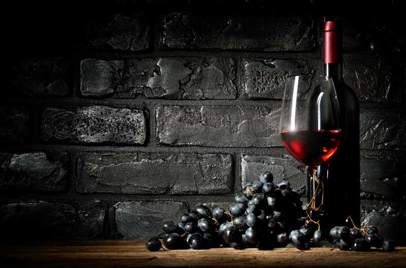 黑砖头背景下的葡萄和葡萄酒