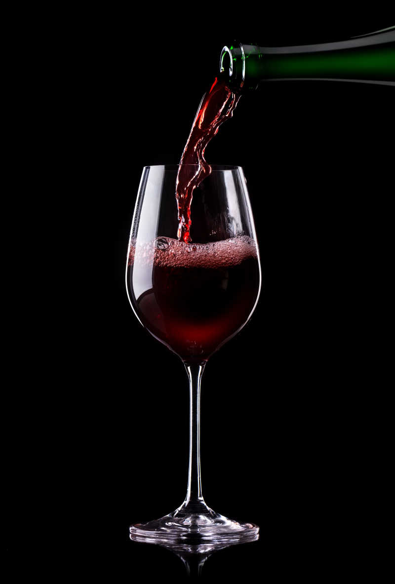 葡萄酒倒入黑色背景的杯子中