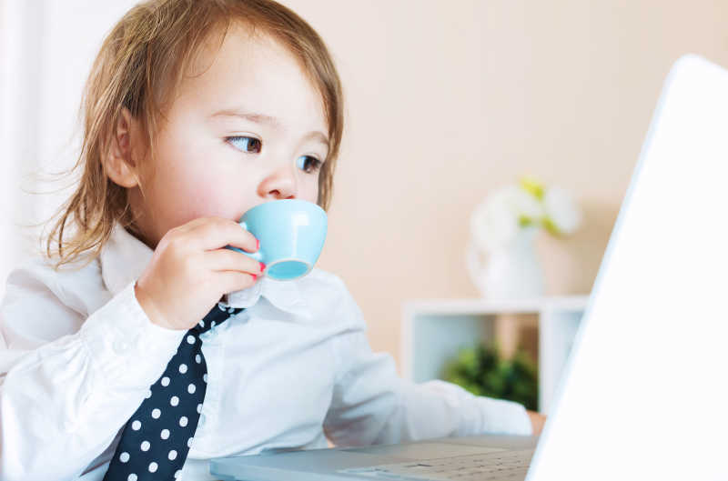 幼儿在笔记本电脑前喝咖啡