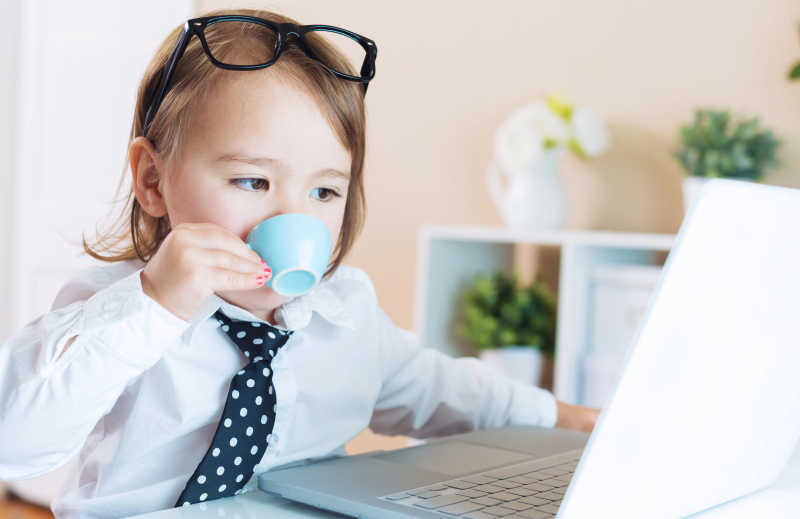 幼儿一边喝咖啡一边使用笔记本电脑